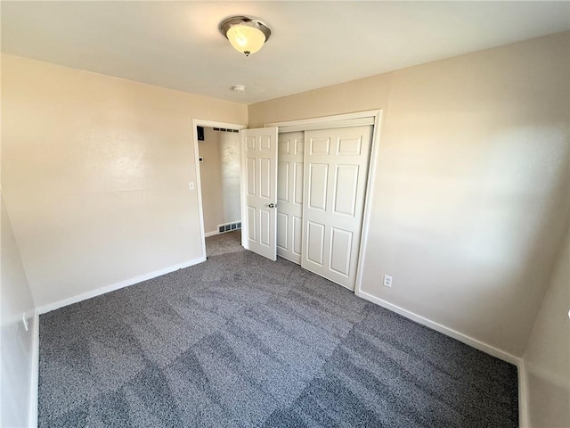 unfurnished bedroom with dark carpet and a closet