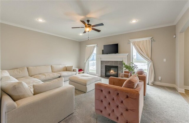 living room featuring light carpet, a fireplace, ornamental molding, and ceiling fan