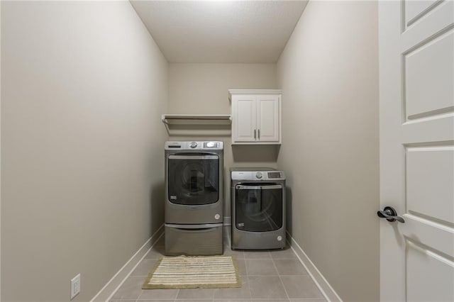 washroom with independent washer and dryer, cabinets, and light tile patterned floors