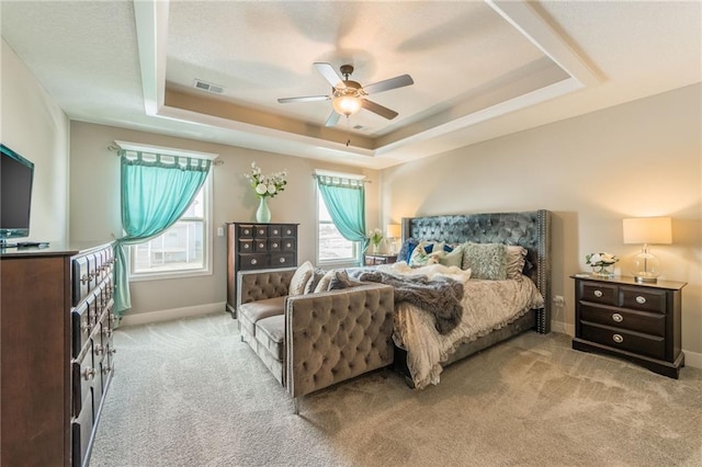 bedroom featuring ceiling fan, light colored carpet, and a raised ceiling