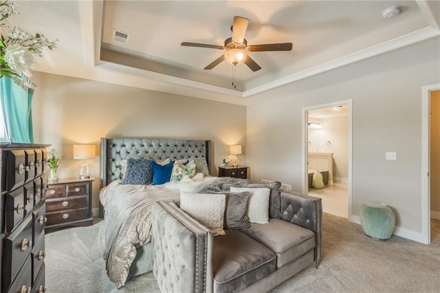 carpeted bedroom featuring a tray ceiling, ensuite bath, and ceiling fan