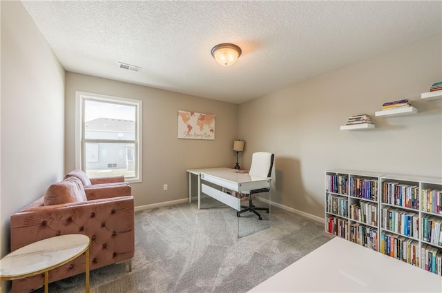 carpeted office featuring a textured ceiling