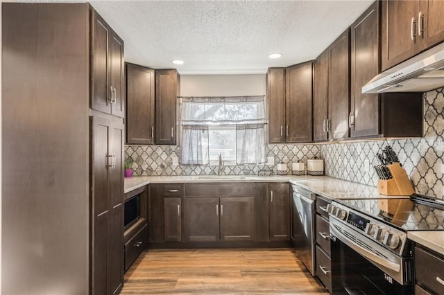 kitchen featuring sink, light hardwood / wood-style flooring, appliances with stainless steel finishes, backsplash, and dark brown cabinetry