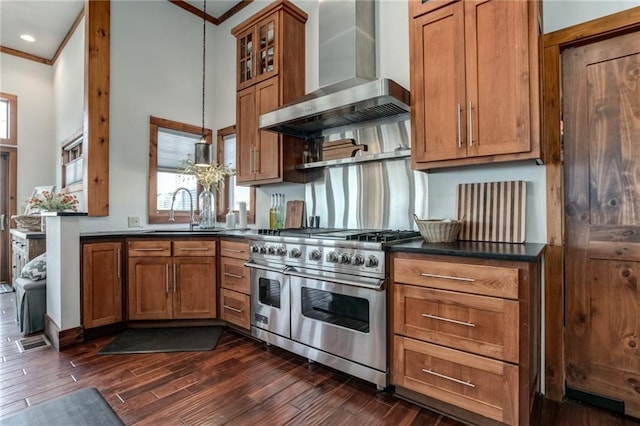 kitchen featuring range with two ovens, dark countertops, ornamental molding, a sink, and wall chimney range hood