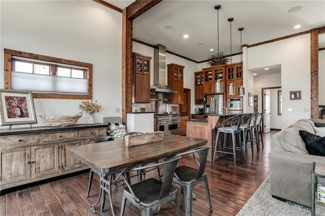 kitchen with dark wood-style flooring, stainless steel appliances, dark countertops, open floor plan, and wall chimney exhaust hood