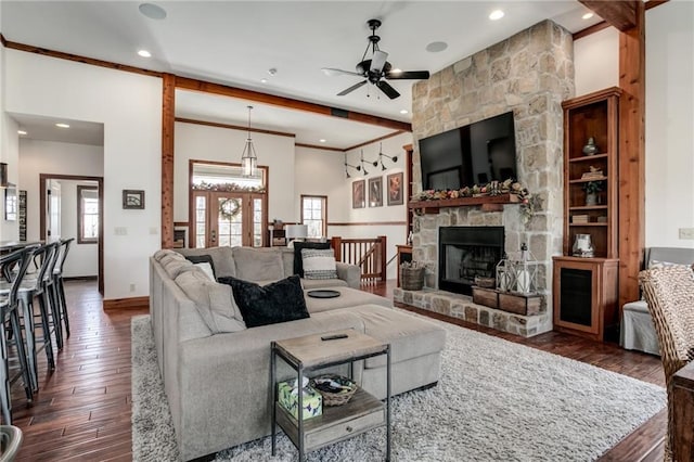 living area featuring dark wood-type flooring, a fireplace, plenty of natural light, and a ceiling fan