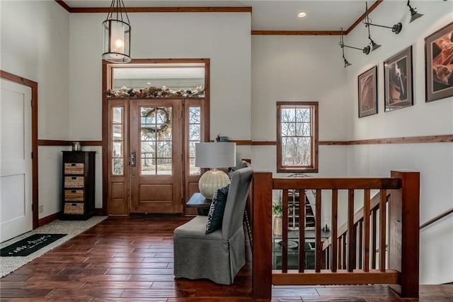 foyer with ornamental molding, wood finished floors, and a high ceiling