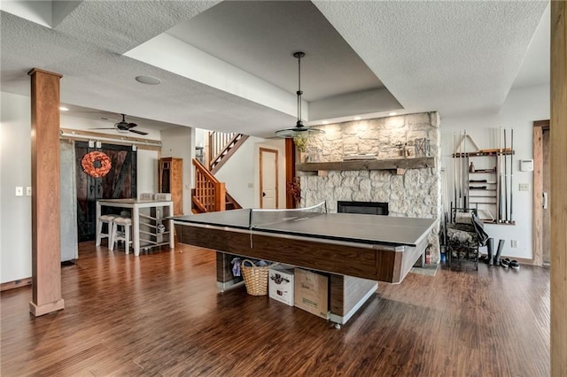 rec room with a fireplace, a raised ceiling, a textured ceiling, wood finished floors, and baseboards