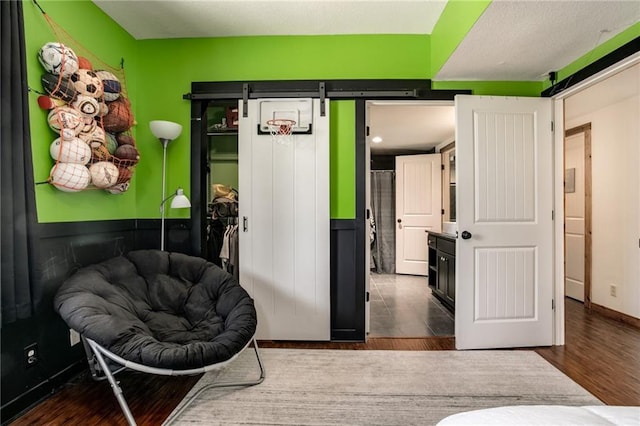 bedroom with a barn door, wood finished floors, and baseboards