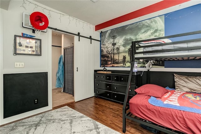 bedroom with a barn door and wood finished floors