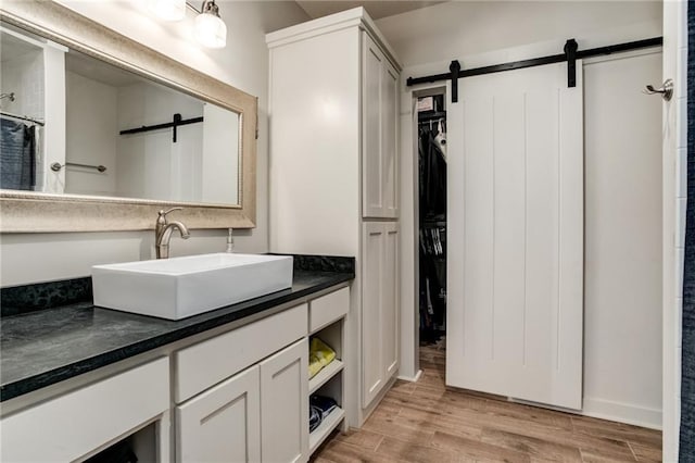 bathroom featuring a spacious closet, vanity, a shower with shower curtain, and wood finished floors