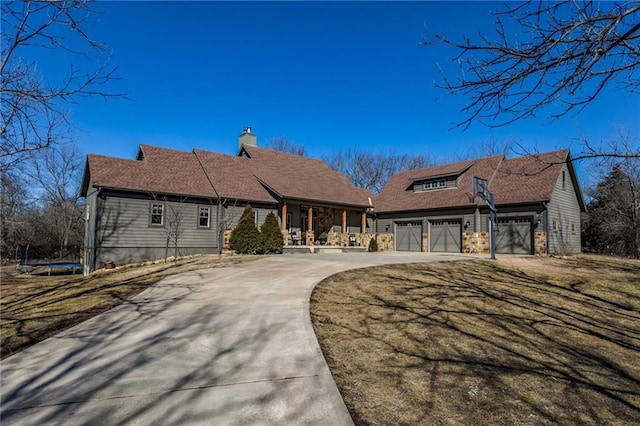 view of front facade featuring a porch, an attached garage, driveway, a trampoline, and a chimney