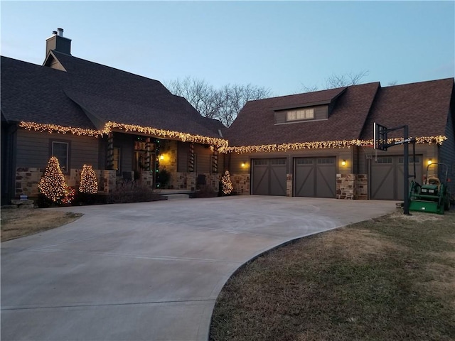 view of front facade featuring an attached garage, stone siding, and driveway