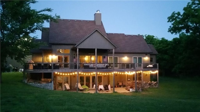 rear view of property featuring a deck, a lawn, a patio area, and a chimney