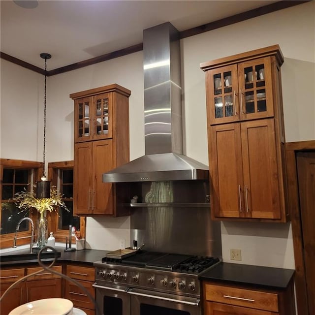 kitchen featuring range with two ovens, dark countertops, brown cabinets, and wall chimney range hood