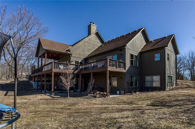 rear view of house with a trampoline, a chimney, and a deck