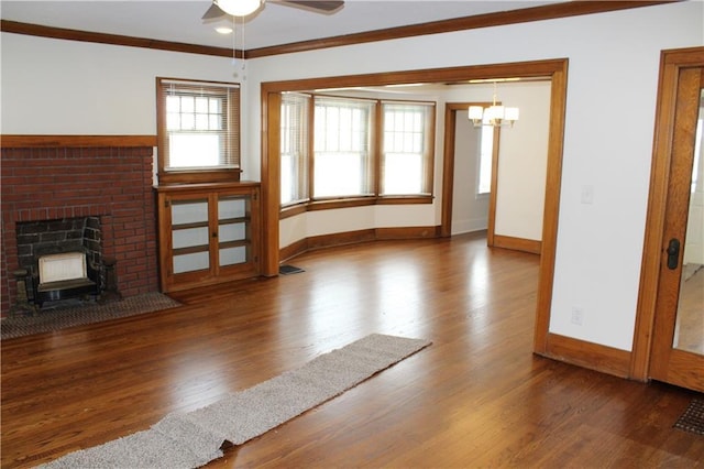 unfurnished living room featuring a fireplace, ceiling fan with notable chandelier, dark hardwood / wood-style floors, and ornamental molding