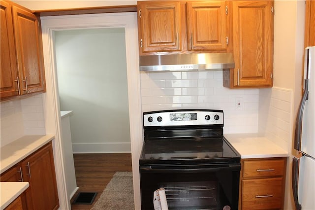 kitchen with hardwood / wood-style floors, decorative backsplash, refrigerator, and black range with electric cooktop