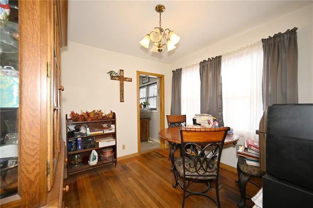 dining space with plenty of natural light, dark wood-type flooring, and an inviting chandelier