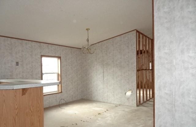 unfurnished dining area featuring ornamental molding and a chandelier