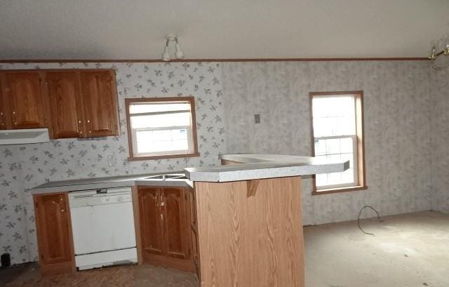 kitchen featuring a wealth of natural light, kitchen peninsula, crown molding, white dishwasher, and a kitchen bar