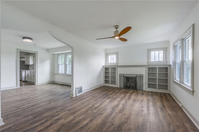 unfurnished living room with a wealth of natural light, crown molding, a fireplace, and dark hardwood / wood-style floors