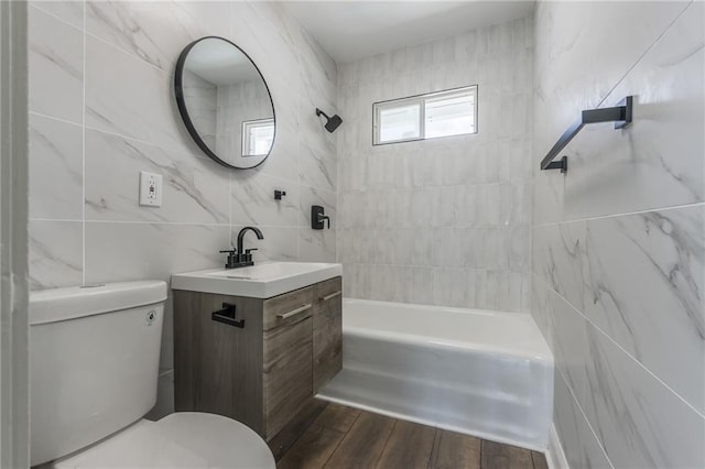 full bathroom with vanity, tiled shower / bath combo, tile walls, and toilet