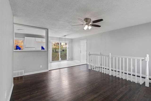 unfurnished room with dark hardwood / wood-style flooring, ceiling fan with notable chandelier, and a textured ceiling