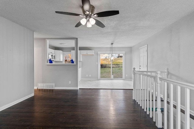 spare room with ceiling fan with notable chandelier and dark hardwood / wood-style flooring