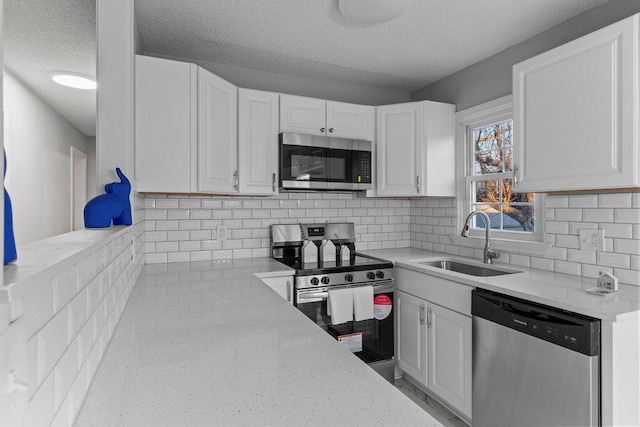 kitchen featuring appliances with stainless steel finishes, a textured ceiling, white cabinetry, and sink