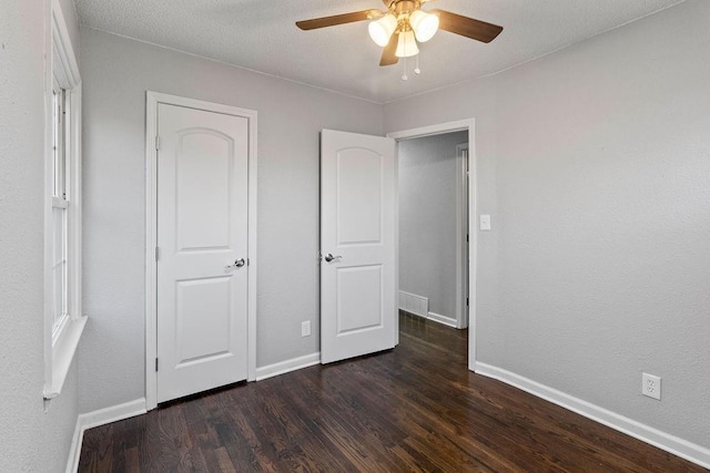 unfurnished bedroom with ceiling fan and dark wood-type flooring