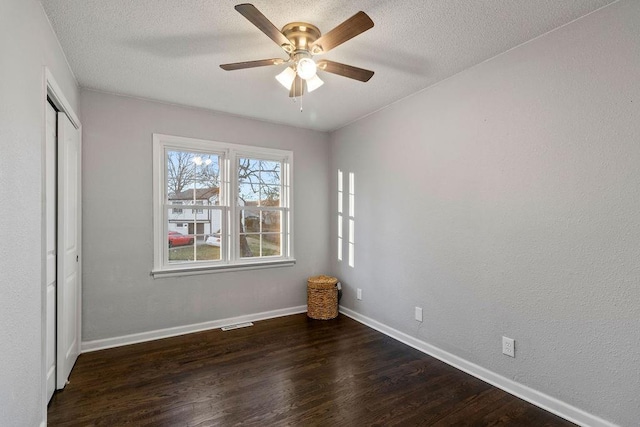 unfurnished room featuring a textured ceiling, ceiling fan, and dark wood-type flooring