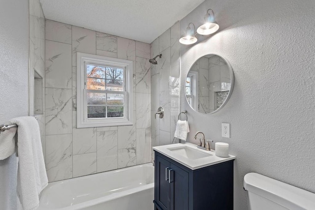 full bathroom featuring vanity, a textured ceiling, tiled shower / bath combo, and toilet