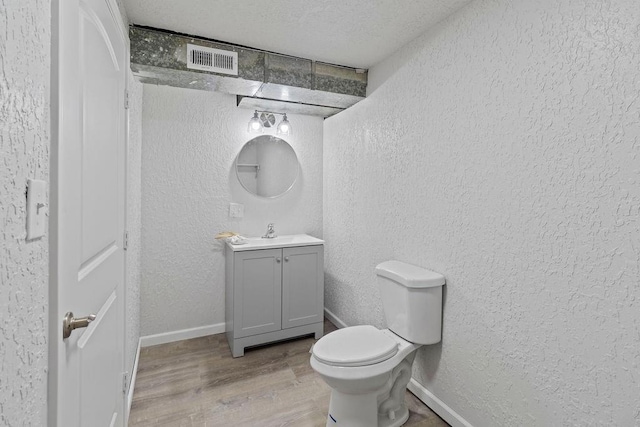 bathroom featuring toilet, vanity, a textured ceiling, and hardwood / wood-style flooring