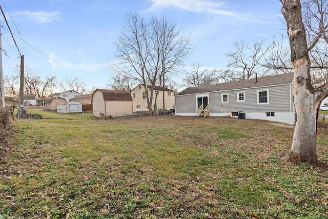 rear view of house with central air condition unit, a yard, and a storage shed