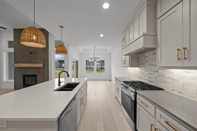 kitchen with premium range hood, sink, an island with sink, pendant lighting, and stainless steel appliances