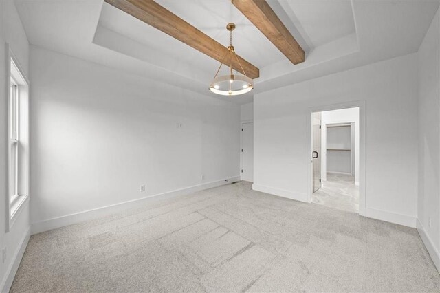 carpeted empty room featuring beam ceiling and a tray ceiling