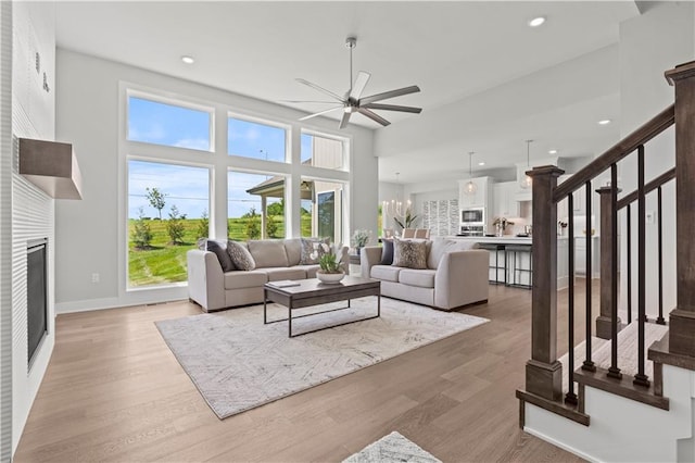 living room with wood-type flooring and ceiling fan with notable chandelier