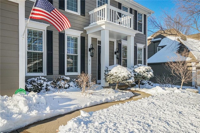 snow covered property entrance with a balcony