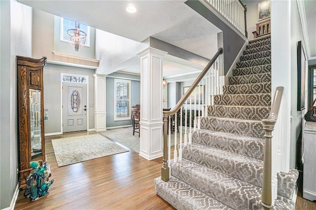 entrance foyer with ornate columns, hardwood / wood-style floors, and a chandelier