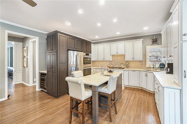 kitchen featuring white cabinetry, sink, stainless steel appliances, a kitchen bar, and a kitchen island with sink