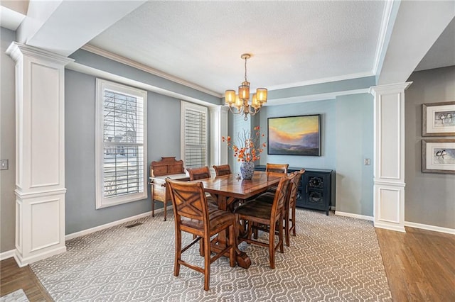 dining space featuring ornamental molding, decorative columns, light hardwood / wood-style flooring, and a notable chandelier