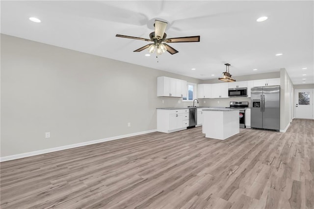 kitchen with pendant lighting, a center island, sink, stainless steel appliances, and white cabinets