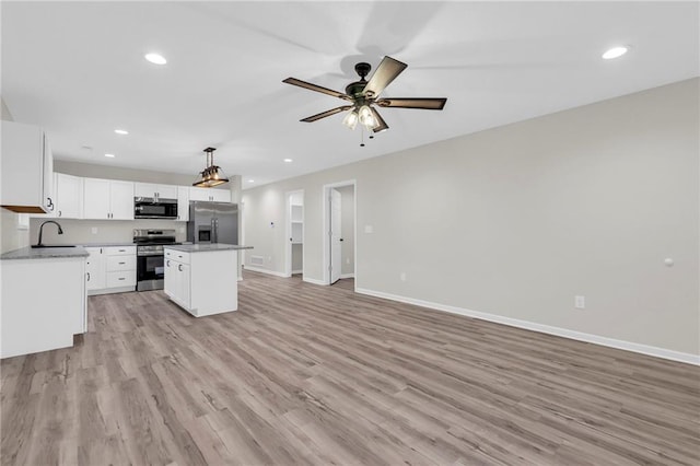 kitchen featuring pendant lighting, a kitchen island, white cabinetry, light wood-type flooring, and appliances with stainless steel finishes