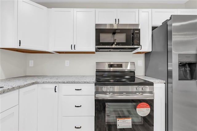 kitchen with stainless steel appliances, white cabinetry, and light stone countertops