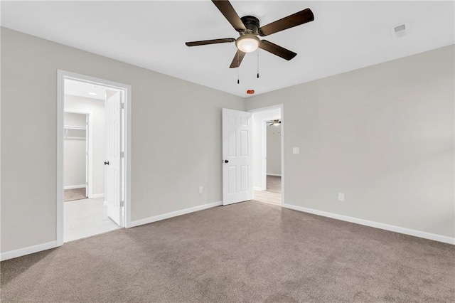 unfurnished bedroom featuring ceiling fan, light colored carpet, a spacious closet, and a closet