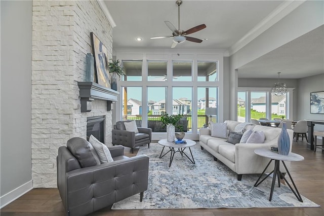 living room featuring crown molding, a fireplace, dark hardwood / wood-style floors, and ceiling fan with notable chandelier