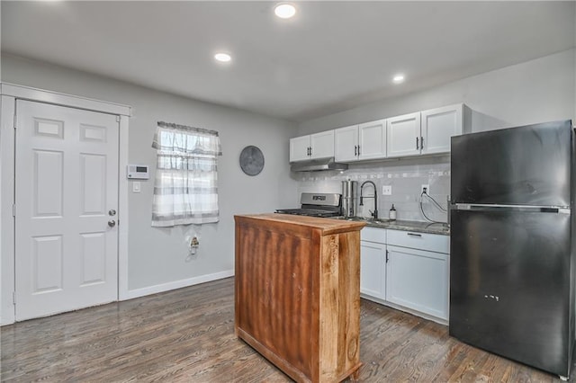 kitchen featuring black refrigerator, white cabinetry, tasteful backsplash, and stainless steel range oven