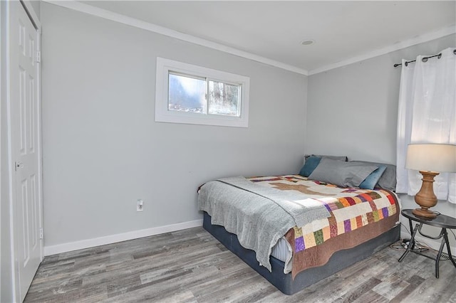 bedroom featuring hardwood / wood-style floors, crown molding, and a closet