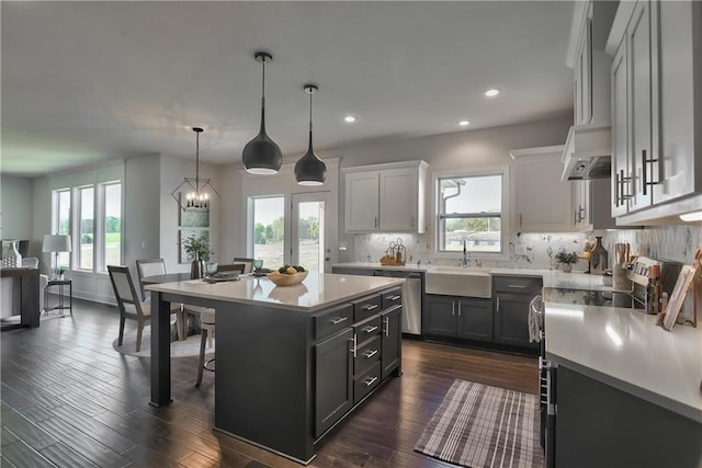 kitchen with sink, hanging light fixtures, stainless steel dishwasher, a notable chandelier, and a kitchen island